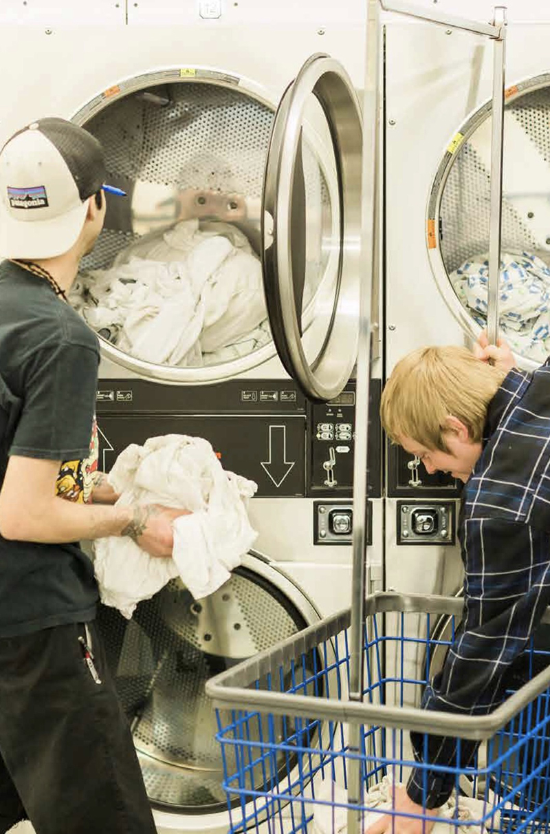 Two men loading laundry into washing machines